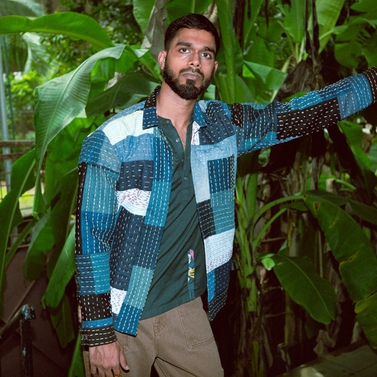 Man wearing a colorful patterned shirt standing among green plants