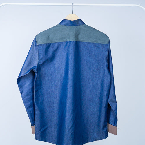 A patterned shirt with various shades of blue and beige patches, displayed on a hanger.