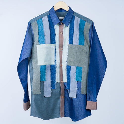 A patterned shirt with various shades of blue and beige patches, displayed on a hanger.